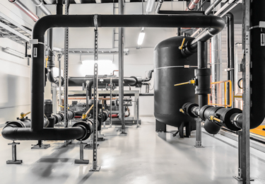 Thermally insulated pipework, valves and system tank in an industrial technical room for thermal insulation applications.