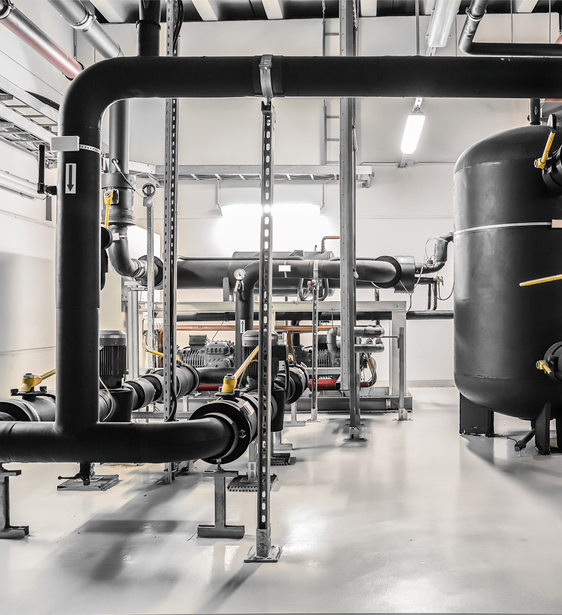 Thermally insulated pipework, valves and system tank in an industrial technical room for thermal insulation applications.