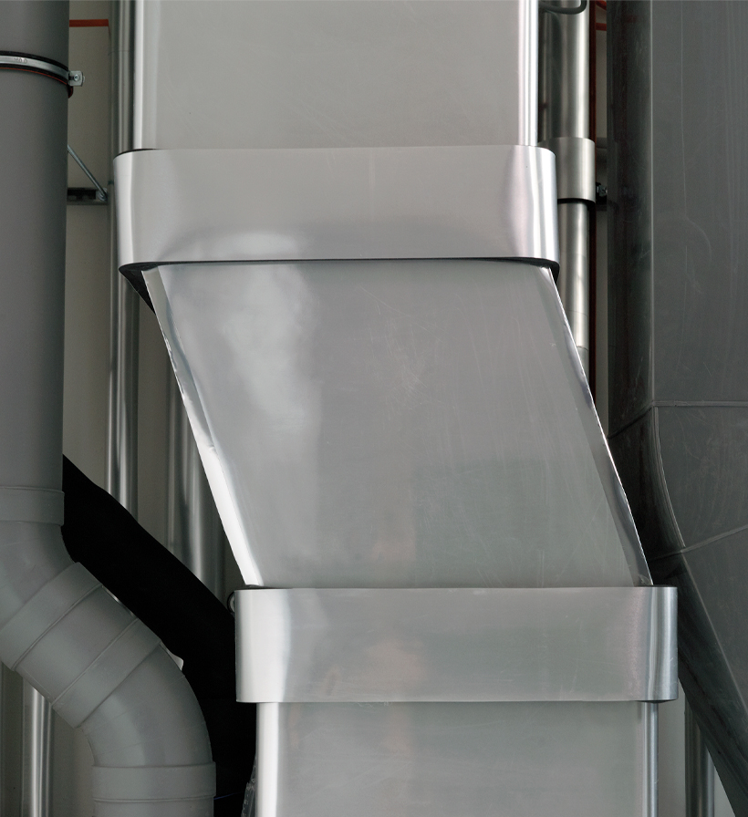 Vertical detail of an HVAC duct with silver facing inside a technical room.